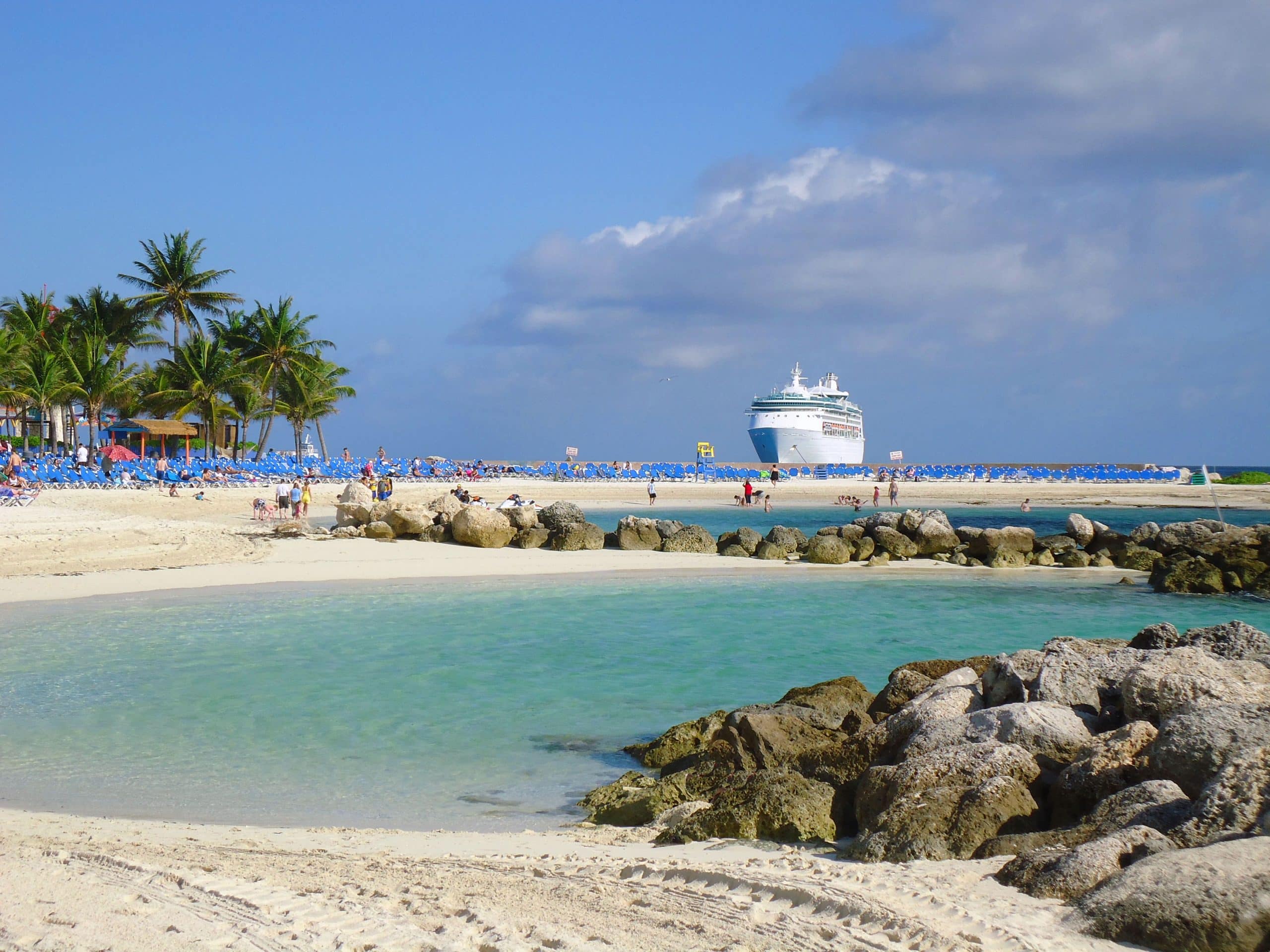 Tropical beach with clear turquoise water and a cruise ship offshore